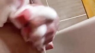 A brunette in the shower touches her pussy and shows her big tits in close-up.